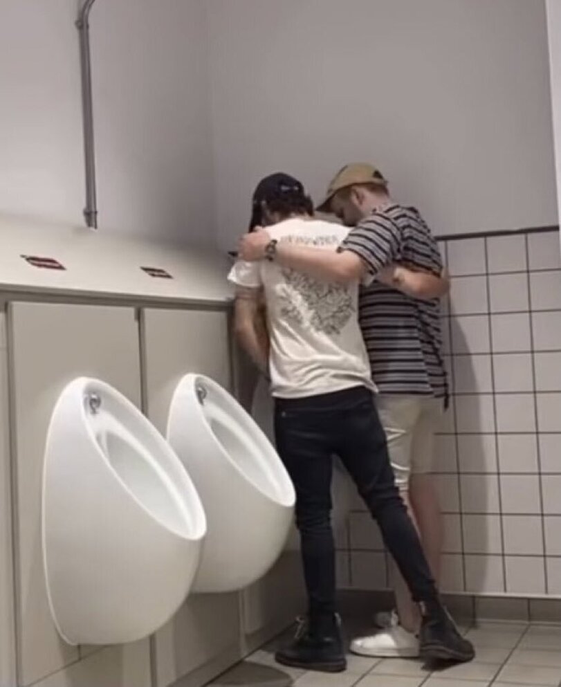 Lustige Kumpels teilen sich ein Pissoir