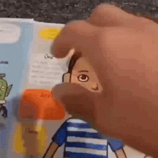 a hand holding a cartoon on a book
