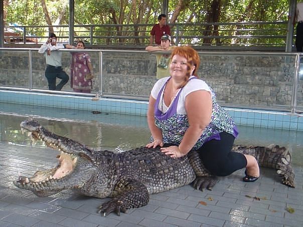 Gequetschtes Krokodil. Übergewichtige Rothaarige Frau auf vor Gewicht ätzendem Krokodil